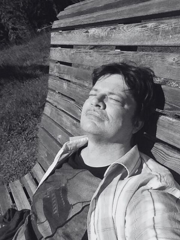 Egy férfi csukott szemmel ül a padon